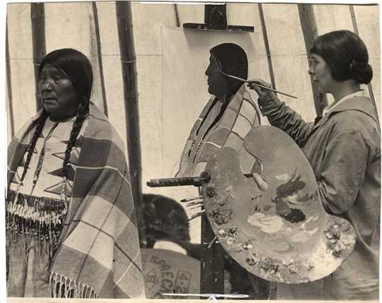 Black and white photograph of Elsa Jemne painting portrait of a Blackfoot woman, c.1915