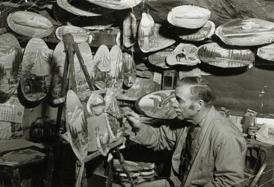 Photograph of Andrew Stenstrom, a lumberjack sky pilot and primitive painter, painting souvenir items in his Bemidji studio c.1940.