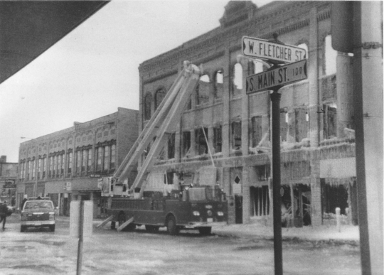 Black and white photograph of a fire truck outside the Opera House Block on South Main Street after the 1987 fire.