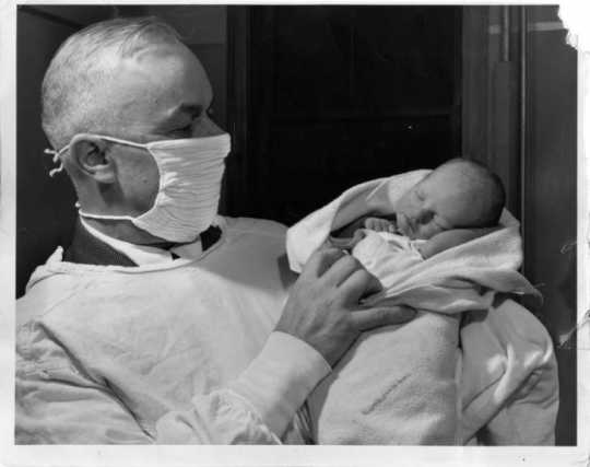 Dr. Russell Heim with a baby left at his office (12 West Lake St., Minneapolis), 1947. Photograph by Paul Siegel. Published in the Minneapolis Morning Tribune, October 31, 1941.