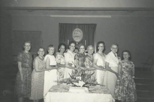 Black and white photograph of ten past BPWC presidents pose for a group photograph, 1961. From left to right: Gudvieg Norseth, Clara Berg, Belva Saugstad, Helen Espe, Clara Caouette, Frances Engebretson, Mae Rideout, Ruth Christenson, Ida Twedten, and Betty Ohman.