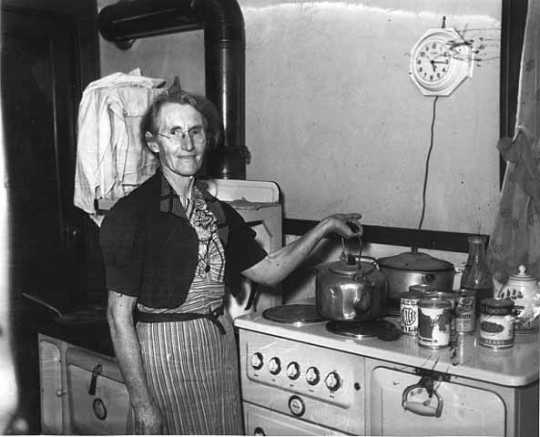 Black and white photograph of a woman standing by an electric stove, 1940. Photographed by the Minneapolis Star Journal.