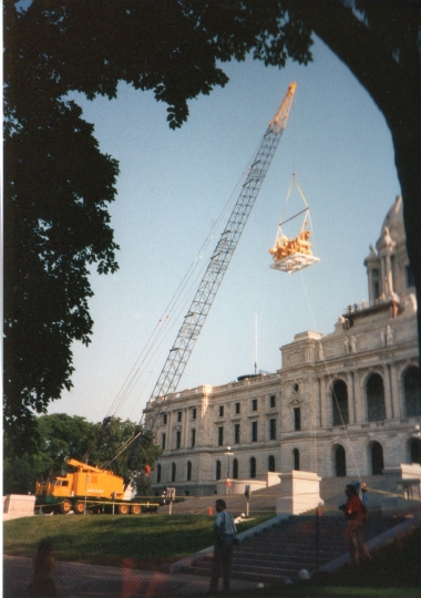 Color image of a construction crane lifting the quadriga into place over the Minnesota State Capitol's front entrance, June 21, 1995. Photographed by Linda A. Cameron