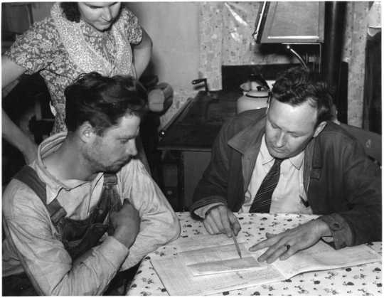 Black and white photograph of a Wilkin County farmer and his wife talk over the farm plan with the Farm Security Administration County Supervisor, ca. 1937.