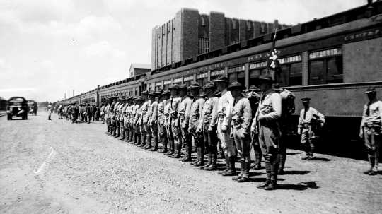 Black and white photograph of guardsmen arriving by train for annual field training at Camp Ripley in 1938.  