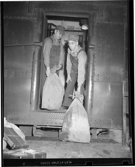 Railway Mail Service clerks load mail bags onto a Great Northern Railway Post Office car at the St. Paul Union Depot.