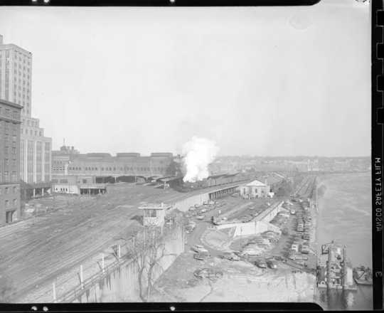 Looking east from the Robert Street bridge at a Milwaukee Road freight train behind double-headed steam locomotives passing the St. Paul Union Depot.