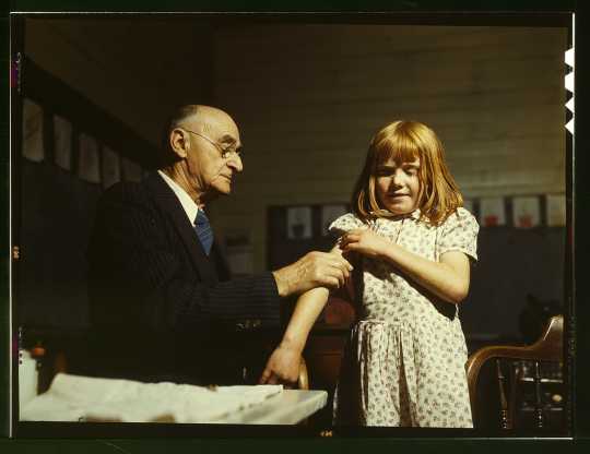 Dr. Schreiber of San Augustine giving a typhoid innoculation at a rural school, San Augustine County, Texas
