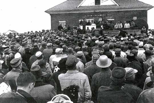 Black and white photograph of a crowd of more than a thousand people gathered on March 7, 1963, in front of the Albion French Lake Creamery.