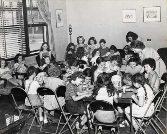Black and white publicity photograph (taken c.1930) showing arts and crafts activates for kids enrolled at "Stay at Home Camp," a summer camp developed by the Jewish Center Activities Association, for the growing number of families joining the J. E. C.