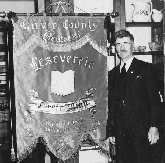 A black and white photograph showing CCHS President O.D. Sell in Mayer with a donated banner from the German Reading Society.