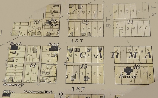 Photograph of page in Polk County plat book (1902) showing locations of Carman’s creamery, hotels, school, and artesian wells.