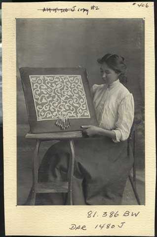 photograph of a young woman displaying bobbin lace