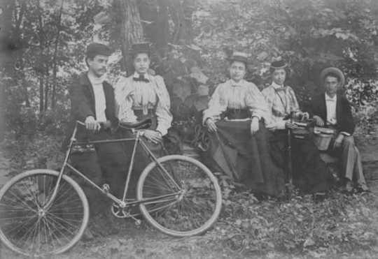 Henrietta Paist and others posed outdoors with a bicycle