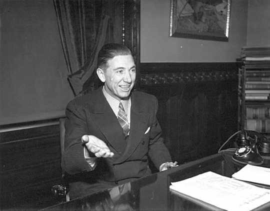 Black and white photograph of Floyd Olson seated at a desk, 1936.