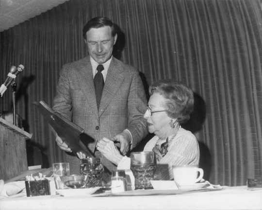 Black and white photograph of Helen E. (Davis) McMillan of Austin receiving a plaque from Martin Sabo at her recognition banquet in Austin, March 18, 1975.