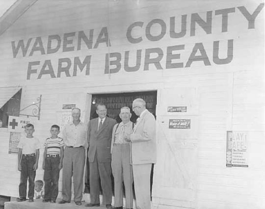 Photograph of Val Bjornson in front of Wadena County Farm Bureau Building with Joe Langer, Fred Miller and others, c. 1954.