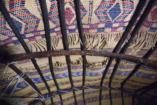 Photograph of the interior roof of an aqal, a traditional Somali home held together by ropes and thick branches and covered with kabad (hand-woven mats)